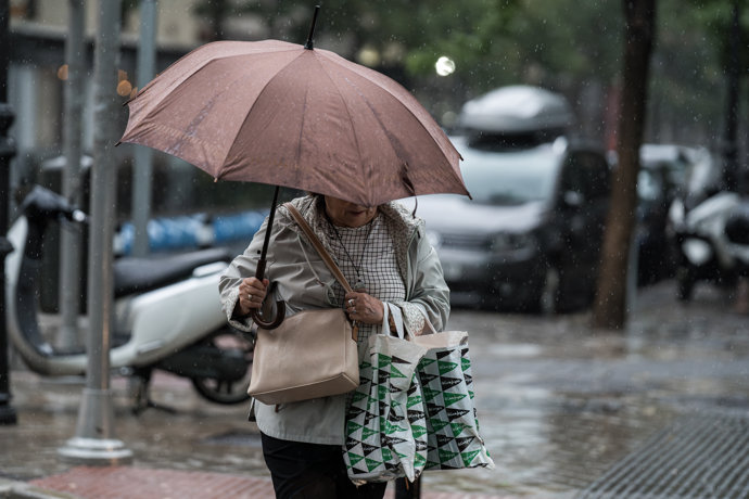Una mujer se resguarda de la lluvia con paraguas.