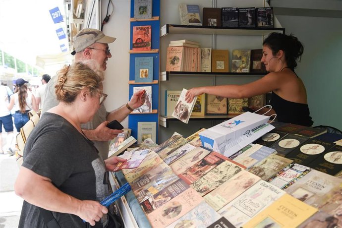 Dos persona observan un libro durante la 84ª Feria del Libro de Madrid, en el parque del Retiro, a 31 de mayo de 2025, en Madrid (España). Esta edición de la Feria del Libro está dedicada a la ciudad de Nueva York y se prolongará hasta el 15 de junio. Ent