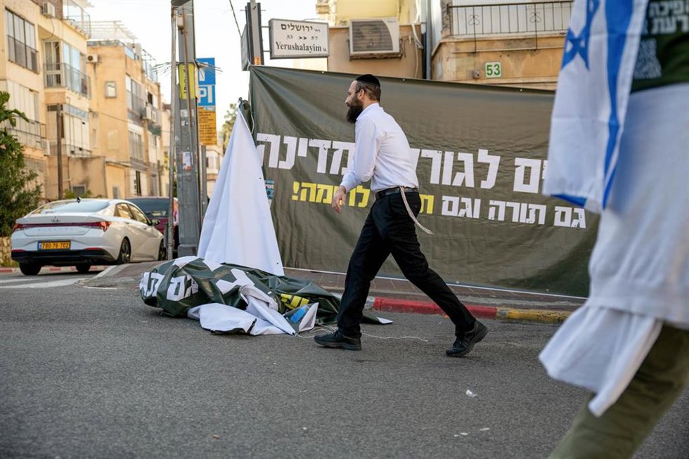 Archivo - Un hombre pasa frente a una pancarta en una protesta en Israel contra la reforma para dejar de eximir a los judíos ultraortodoxos del servicio militar obligatorio 