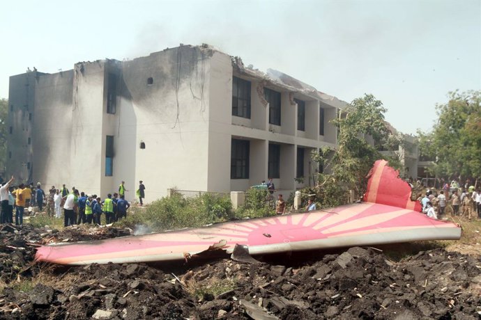 Un grupo de personas cerca de los restos del avión de la aerolínea Air India con destino a Londres que se estrelló poco después de despegar del aeropuerto de la ciudad de Ahmedabad, en India