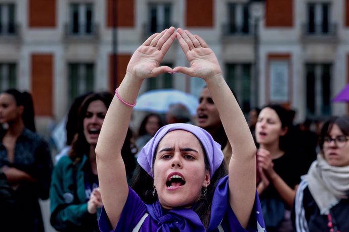 Archivo - Una mujer protesta haciendo un símbolo feminista con las manos durante una concentración en la Puerta del Sol, Madrid.