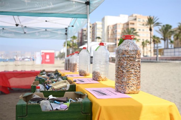 Botellas llenas de colillas y cajas con residuos recogidos del arenal, expuestas en la playa de El Palmeral, en Almería.