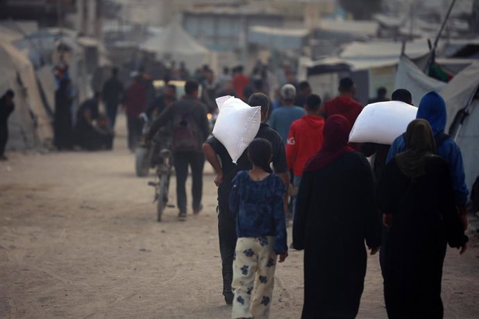Colas de palestinos transportan sacos de ayuda en ciudad de Gaza 