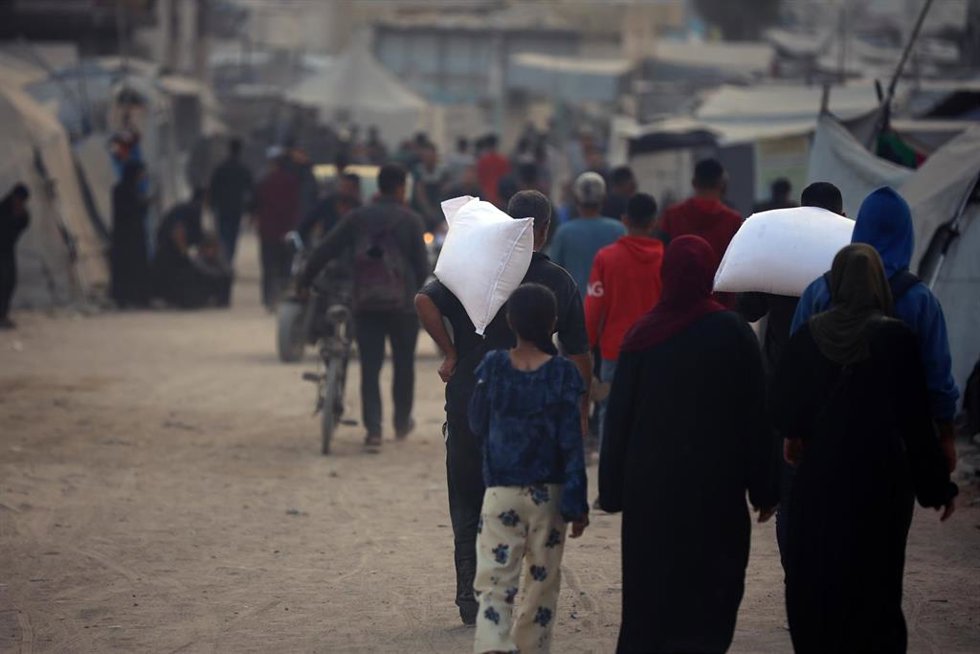 Colas de palestinos transportan sacos de ayuda en ciudad de Gaza