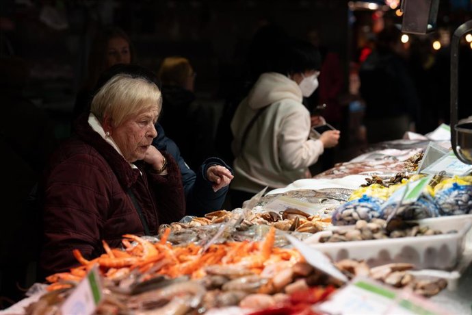 Archivo - Una señora mira el género expuesto, en el Mercado de la Boquería.