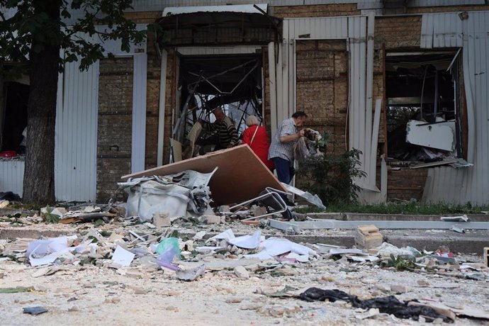 Varias personas recogen escombros en Kiev tras un ataque ruso