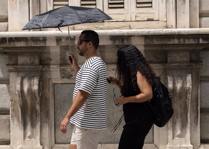 Archivo - Un hombre se resguarda del sol bajo un paraguas, a 18 de julio de 2024, en Madrid (España). La primera ola de calor del verano pone hoy en aviso amarillo o naranja a casi toda España, con temperaturas que superarán los 40 grados en algunos punto