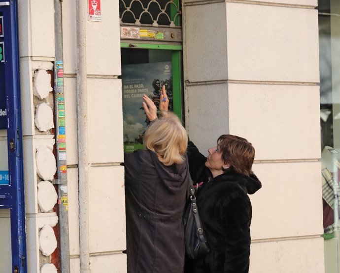Archivo - Dos mujeres cierran la persiana de su negocio