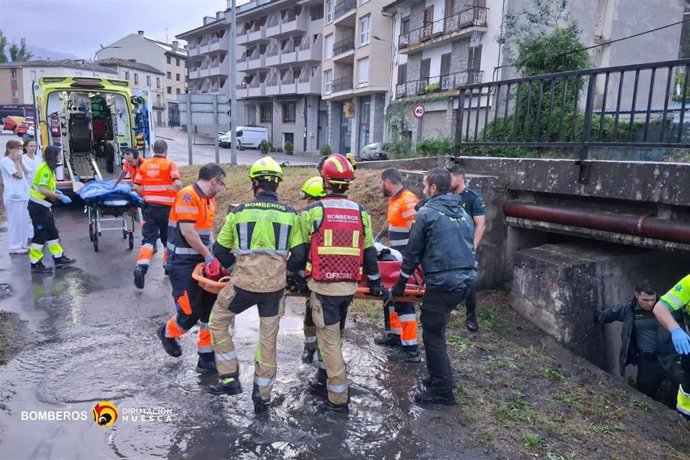 Personal médico del 061 y del centro de salud de Aínsa,  bomberos de la DPH y la Guardia Civil asisten al joven que ha caído este domingo al río Ara en Aínsa (Huesca).