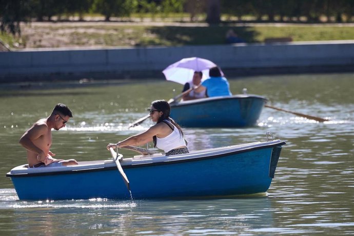Archivo - Dos personas en una barca del largo del parque de El Retiro durante una segunda ola de calor, a 23 de julio de 2024, en Madrid (España).