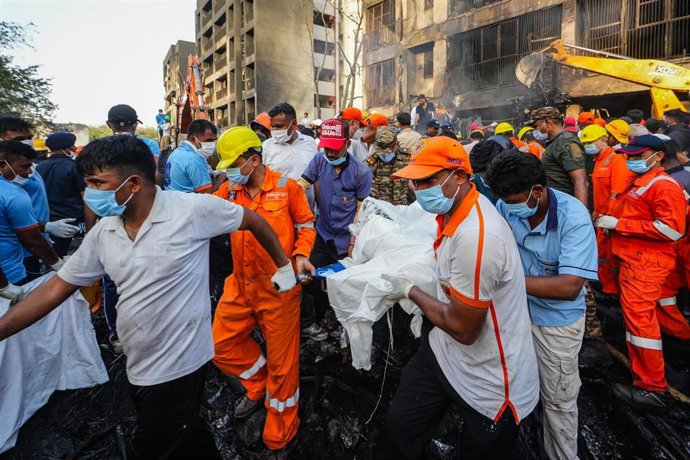 Un grupo de personas traslada a una de las víctimas del vuelo de Air India siniestrado.