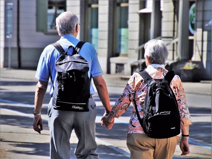 Pareja de personas mayores llevando mochilas.