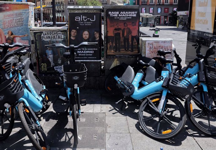 Archivo - Arxiu - Una dona passa amb el seu telèfon mòbil per diversos cartells de concerts
