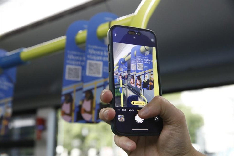 Una persona escanea con su móvil uno de los códigos QR de la campaña Tu biblioteca a un clic del Ayuntamiento de Madrid