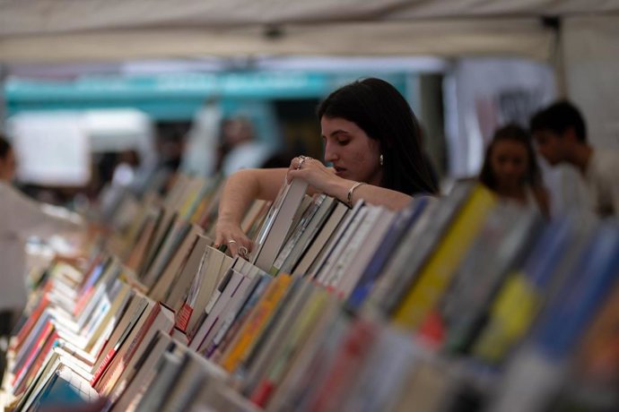 Una joven mira un libro de un expositor