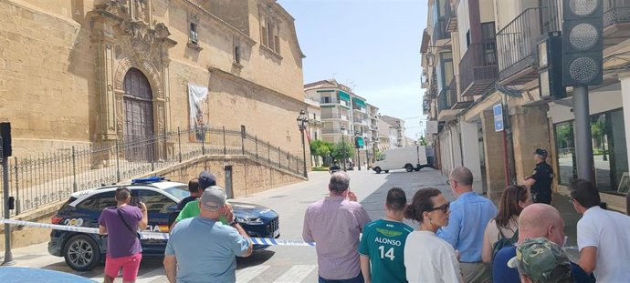 Varias personas observan el trabajo de los agentes tras el cordón de seguridad.