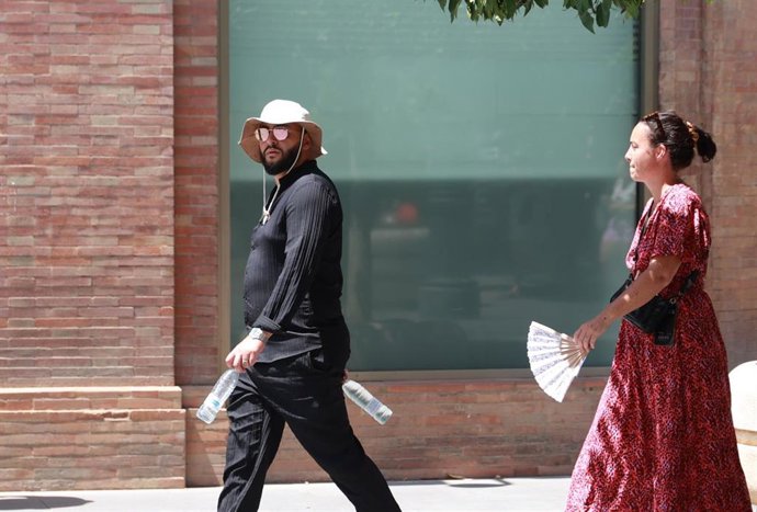 Archivo - Dos personas caminan por la calle en una jornada de altas temperaturas.