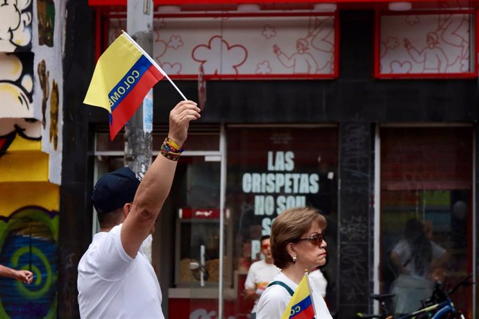 Manifestante ondea una bandera de Colombia en una marcha en repulsa por el atentado contra el senador colombiano Miguel Uribe Turbay