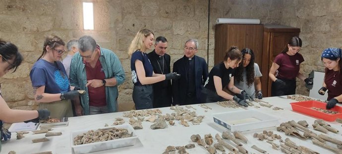 El obispo de Palencia y los responsables del estudio osteoarqueológico, revisan los restos junto a los alumnos.