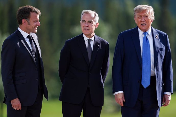 June 16, 2025, Kananaskis, Ab, CANADA: French President Emmanuel Macron, left, and Canadian Prime Minister Mark Carney, centre, listen as U.S. President Donald Trump responds to questions from reporters after posing for the family photograph during the G7