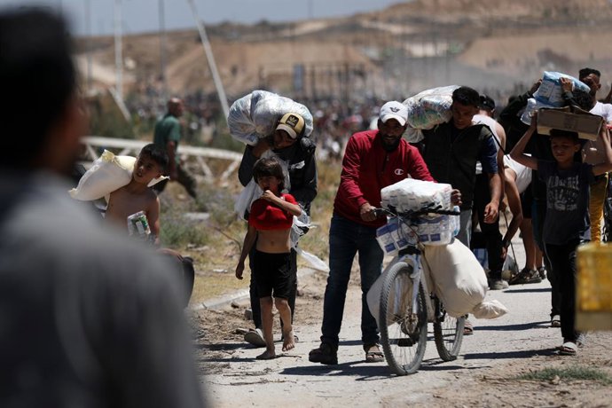 29 de maio de 2025, Bureij, Faixa de Gaza, Território Palestino: Palestinos caminham com suprimentos de ajuda que receberam da Gaza Humanitarian Foundation, apoiada pelos EUA, em Al-Bureij, no centro da Faixa de Gaza. Os ataques israelenses mataram pelo m