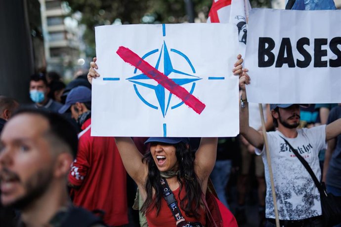 Archivo - Varias personas sostienen en Madrid pancartas durante una manifestación contra una cumbre de la OTAN en 2022.