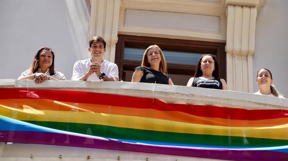 El portavoz del PSPV-PSOE en el Ayuntamiento de Valncia, Borja Sanjuán, y la secretaria general de la formación en la ciudad, Pilar Bernabé, junto a la bandera LGTBI de 60 metros desplegada en el balcón de su grupo municipal.