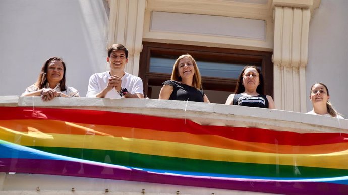 El portaveu del PSPV-PSOE a l'Ajuntament de València, Borja Sanjuán, i la secretària general de la formació en la ciutat, Pilar Bernabé, junt amb la bandera LGTBI de 60 metres desplegada en la balconada del seu grup municipal.