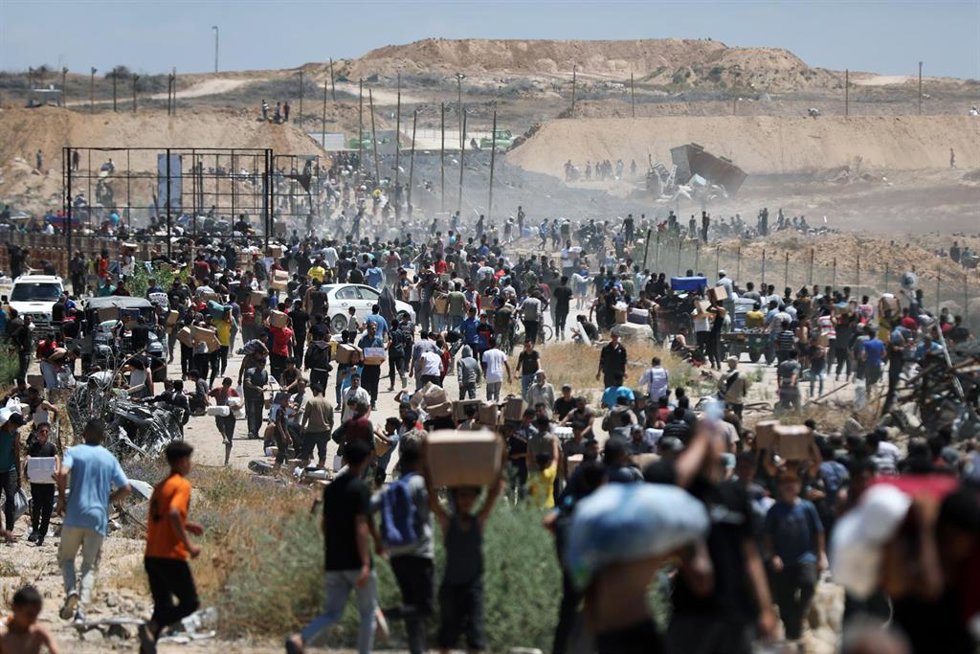 Palestinos cargan con ayuda entrengada por GHF, fundación respaldada por Israel y EEUU, en Al Bureij, en el centro de la Franja de Gaza