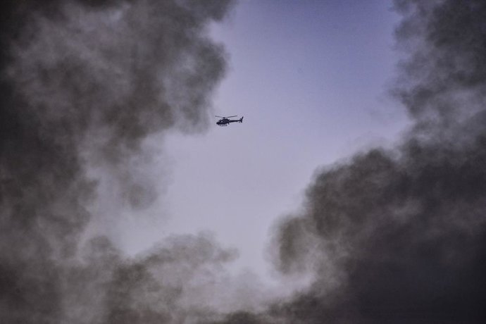 June 17, 2025, Central Israel, Israel: An Israeli helicopter flies next to black smoke that arose from a direct missile hit following an Iranian ballistic missile barrage. Israel launched a sweeping assault on the heart of Iran's nuclear and military stru