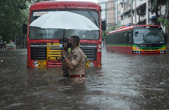 Archivo - May 17, 2021, Mumbai, India: A policeman helps a public transport driver to cross a flooded street due to heavy rain caused by Cyclone Tauktae in Mumbai. Strong winds and heavy rain lashed Mumbai and its neighboring areas today morning due to a 