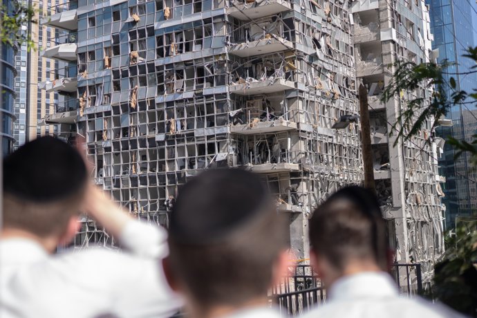 19 June 2025, Israel, Ramat Gan: Israelis stand in front of a building damaged by an Iranian missile on Ramat-Gan. Photo: Ilia Yefimovich/dpa