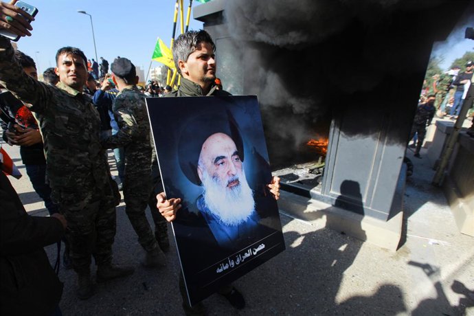 Archivo - Arquivo - Um homem caminha em Bagdá com um pôster do principal clérigo xiita do Iraque, Ali al-Sistani (arquivo).