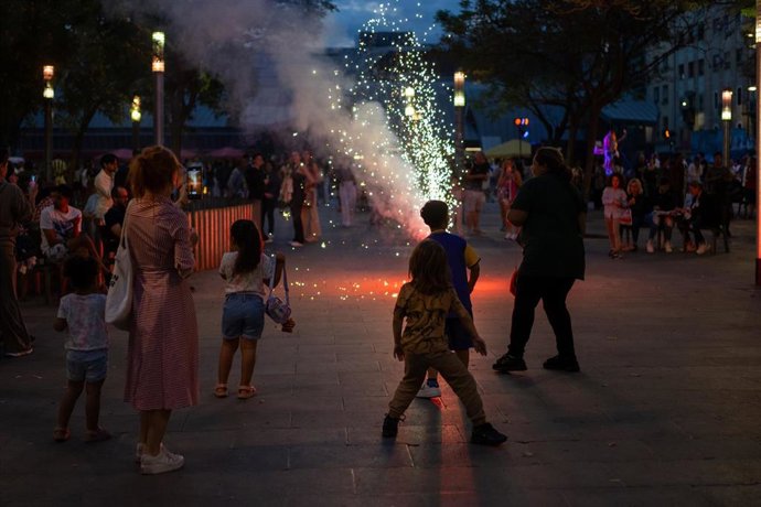 Archivo - Unas personas encienden petardos durante la verbena de San Juan