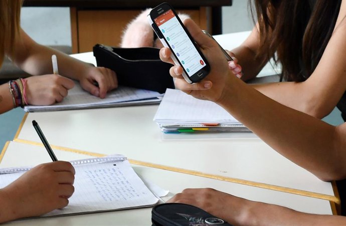 Archivo - FILED - 22 June 2017, Berlin: A student holds a mobile phone during a lesson at a classroom. President of the German Teachers' Association, Heinz-Peter Meidinger, told the German Press Agnecy (dpa) that school students in Germany learn too littl