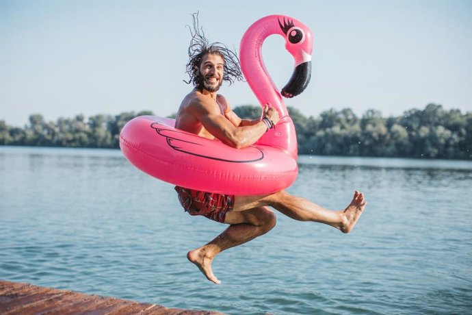 Archivo - Hombre se va a zambullir en el agua con un flotador.