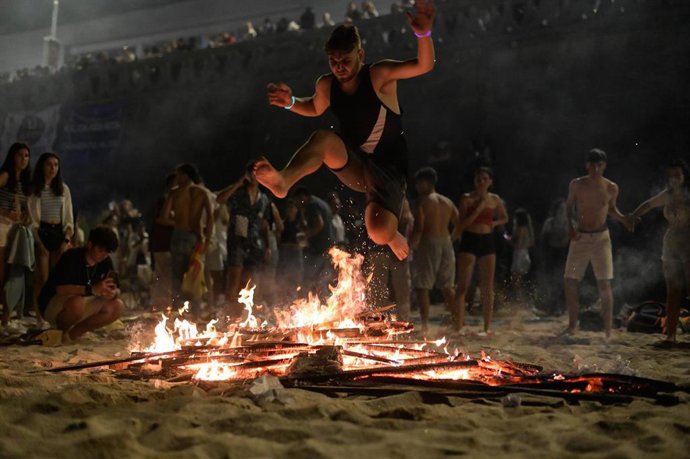Archivo - Una persona salta una hoguera durante la Noche de San Juan, en la playa de Riazor, a 23 de junio de 2023, en A Coruña, Galicia (España). 