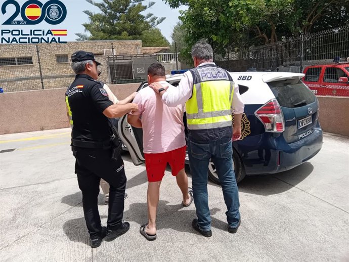 Agentes de la Policía Nacional acompañan al vehículo policial a uno de los detenidos en Playa de Palma por robar a turistas y luego usar las tarjetas de crédito sustraídas