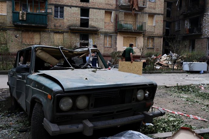 18 de junho de 2025, Kiev, Ucrânia: Um homem carrega madeira compensada em frente a um carro destruído perto de um prédio residencial que foi fortemente danificado por um ataque de míssil russo no dia anterior, em Kiev, em meio à invasão russa na Ucrânia.