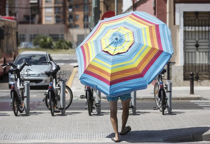 Archivo - Un hombre con una sombrilla cerca de la Playa de la Malvarrosa, a 12 de agosto de 2022, en Valencia