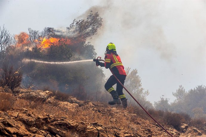 Archivo - ATHENS, Aug. 12, 2024  -- A firefighter tries to extinguish a wildfire in Attica, Greece, on Aug. 12, 2024.   A large wildfire reached a dozen suburbs of the Greek capital Athens on Monday, leading to the evacuation of thousands of people.    Th