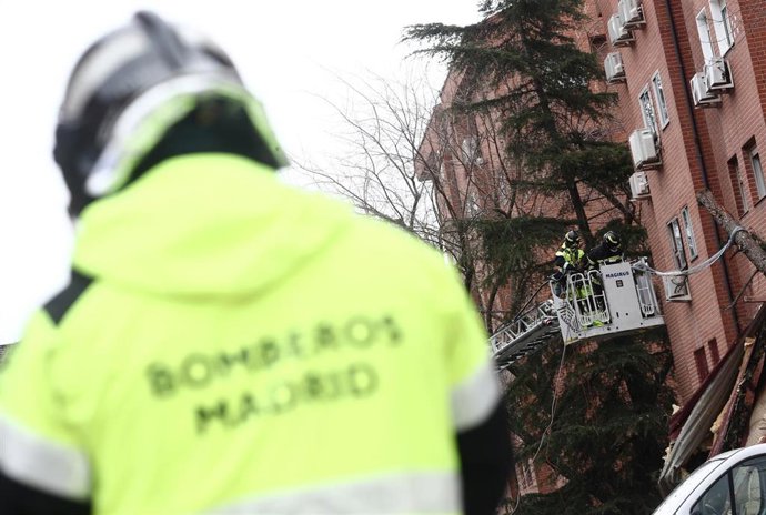 Archivo - Un bombero de la Comunidad de Madrid camina en la zona donde varios compañeros inspeccionan una de las ventanas del edificio que ha perdido la cubierta de su tejado arrancado por el viento, en el distrito de Villa de Vallecas, en Madrid, (España