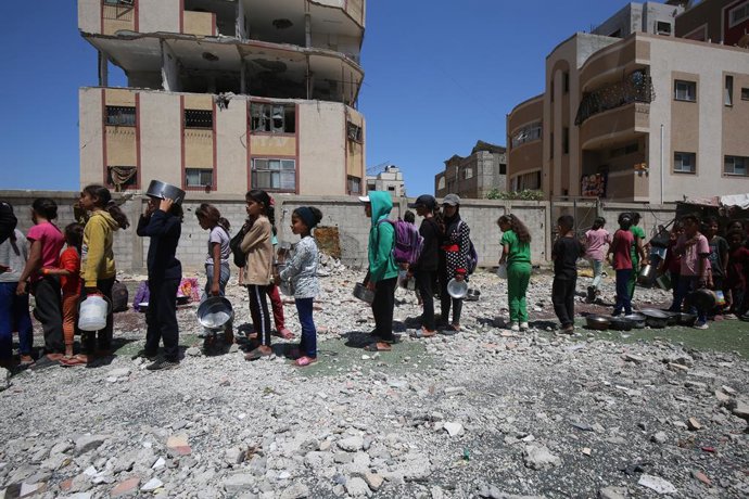 30 de maio de 2025, Nuseirat, Faixa de Gaza, Território Palestino: Palestinos deslocados internamente se reúnem em uma cozinha beneficente para receber rações limitadas em meio à escassez de alimentos, no campo de refugiados palestinos de Nuseirat, no cen