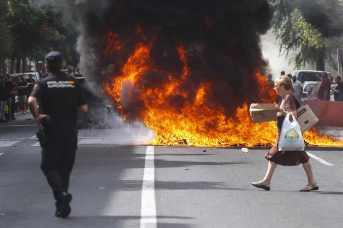 Una mujer cruza la calle donde hay una barricada con contenedores de basura hecha por huelguistas del metal en Cádiz. ARCHIVO.