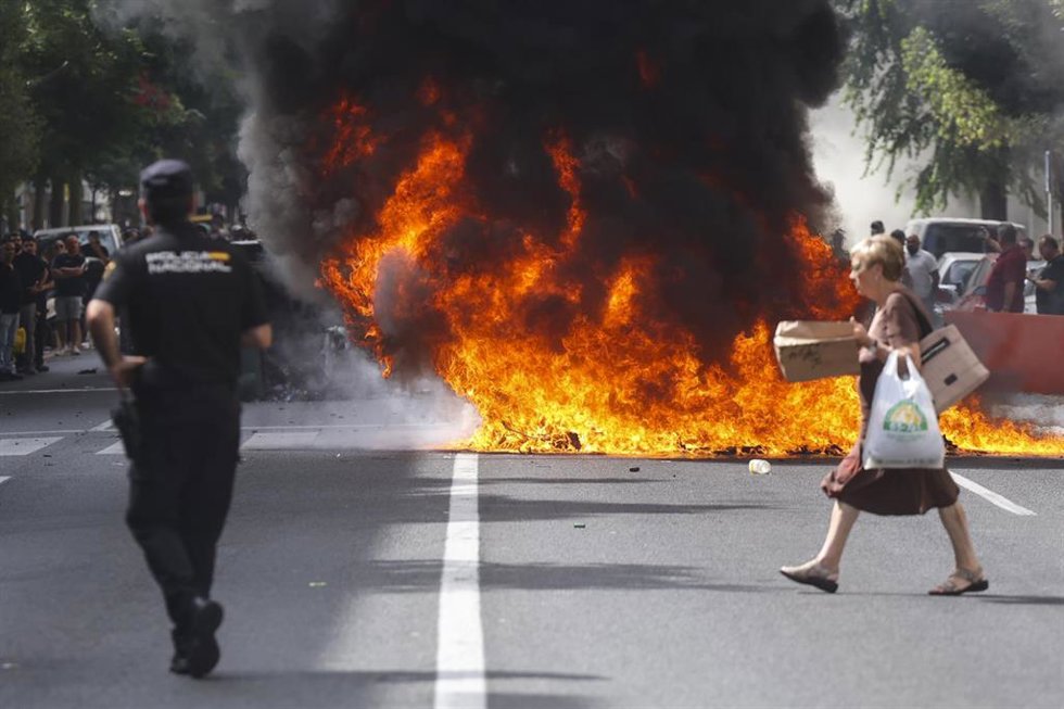 Una mujer cruza la calle donde hay una barricada con contenedores de basura hecha por huelguistas del metal en Cádiz. ARCHIVO.