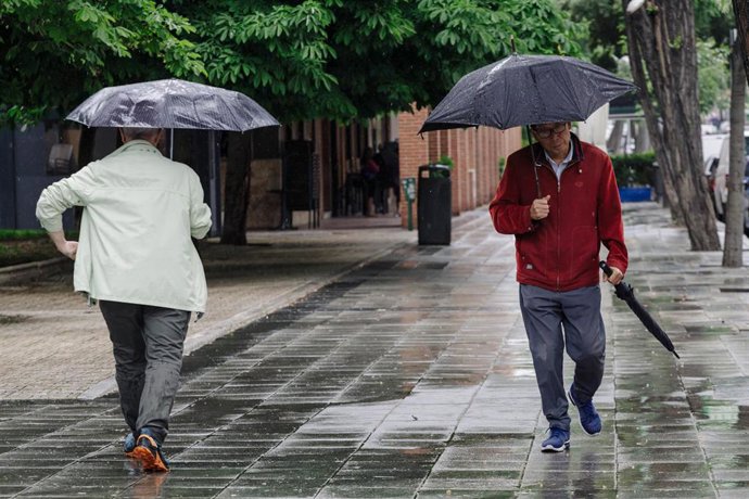 Archivo - Dos personas pasean bajo la lluvia, a 23 de mayo de 2023, en Madrid (España). La Agencia Estatal de Meteorología (Aemet) prevé lluvias en la región madrileña todo lo que queda de semana ocasionadas por una DANA (Depresión Aislada en Niveles Alto