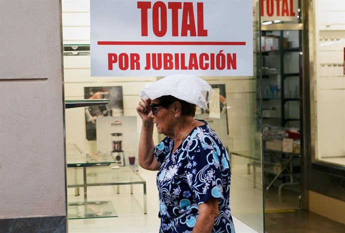 Archivo - Una mujer camina cubierta por la calle durante una jornada de lluvia.