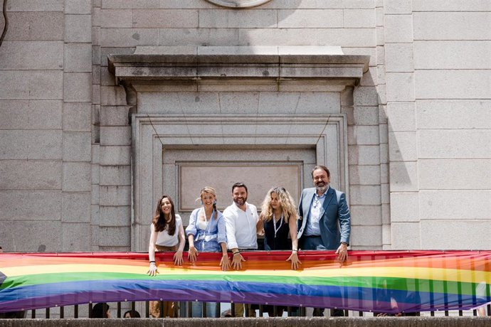 La vicepresidenta segunda y ministra de Trabajo y Economía Social, Yolanda Díaz, y la secretaria de Estado de Economía Social, Amparo Merino, despliegan la bandera LGTBI+
