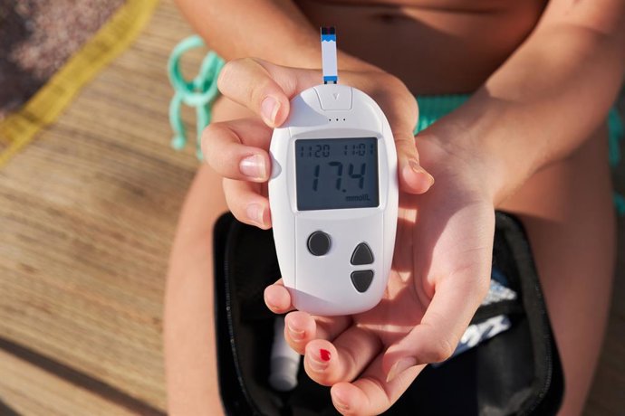 Archivo - Una chica diabética se revisa el nivel de azúcar en la sangre sentada en la playa en verano. Tratamiento y control de la diabetes mellitus, atención médica. Estilo de vida para diabéticos.