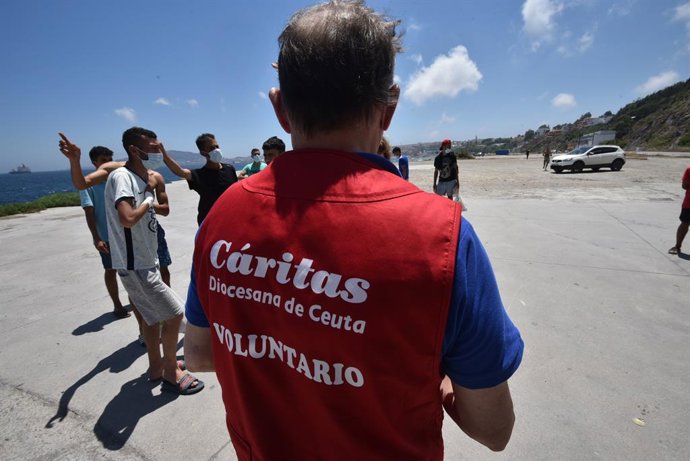Archivo - Un trabajador de Cáritas Diocesana reparte alimentos a migrantes que entraron a Ceuta hace 3 semanas, a 7 de junio de 2021, en Ceuta, (España). La ONG de la iglesia, que atiende las necesidades de alrededor de 400 migrantes en Ceuta, realiza un 